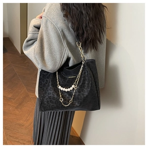 Detailed view of black leopard print tote with pearl chain and golden flower charms