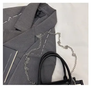 Flat lay of a black leather handbag with silver chain detail on a grey suit jacket
