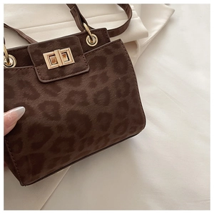 Detailed view of dark leopard print suede shoulder bag with golden metal twist lock