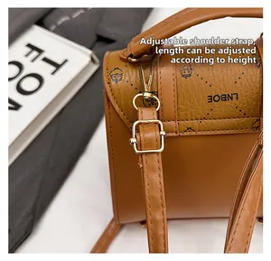 Detail view of adjustable leather shoulder strap with metal buckle and logo texture