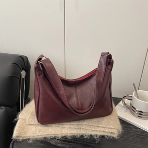 Vintage burgundy faux leather hobo bag with gold hardware on a minimalist background
