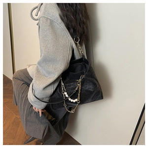 Detail of black leopard embossed leather tote bag with elegant pearl and clover chain strap