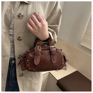 Close-up of vintage brown leather bowling bag with gold buckle and rivet details