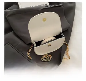 Detail showing internal space of white saddle bag with magnetic buckle and gold chain