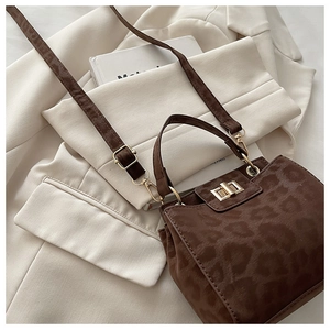 Close-up of leopard pattern texture and golden turn-lock closure on a brown satchel