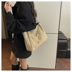 Detail of beige faux suede tote bag featuring elegant gold chain and pearl strap accents