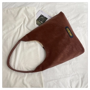 Detail view of coffee brown faux leather tote bag with yellow JACQEUE embroidery logo
