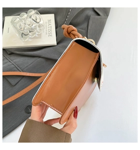 Side view of bicolor crossbody bag showing accordion structure and knotted strap details