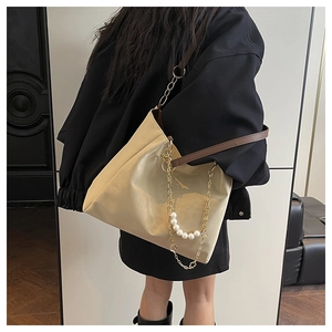 Detail of beige tote bag with a decorative pearl and gold floral charm chain