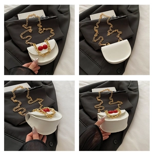 Detail view of white saddle bag with cherry charm and golden chain strap in various angles