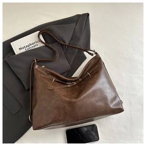 Detail of vintage brown PU leather tote bag with smooth texture and sturdy shoulder strap