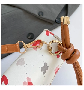 Detail of white leather shoulder bag with red hearts, Mickey print and gold metal buckles