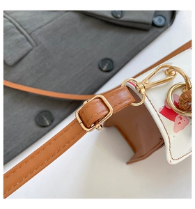Close-up of golden metal hooks and brown leather strap on a cartoon bear pattern bag