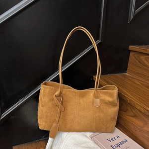 Brown suede tote bag with leather straps and knot charm in a minimalist vintage style