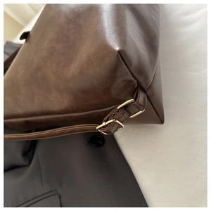 Détail du sac cabas en cuir marron foncé avec texture vintage et boucle dorée
