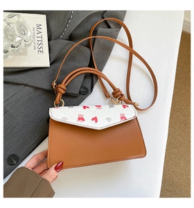 Detail of brown leather handbag with pink bear print on grey suit with Matisse book