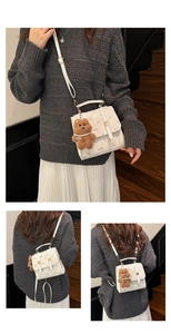 Detail of white crossbody bag with brand monogram print and brown plush bear charm