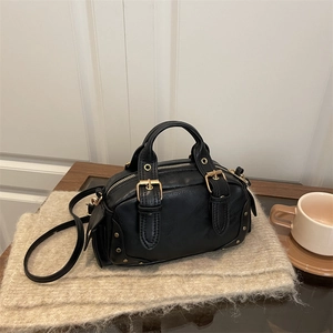 Retro black leather bowling bag with gold hardware on a minimalist beige background