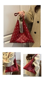 Close-up of red leather hobo bag with gold rivet accents and stylish triangular shape