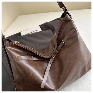 Gros plan du sac cabas marron foncé aspect cuir huilé avec boucles et œillets en métal