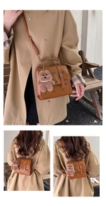 Close-up of vintage brown leather bag with LNBOE print and cute plush bear charm