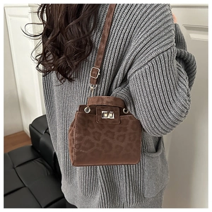 Brown leopard print crossbody bag with silver clasp shown on a grey knit sweater