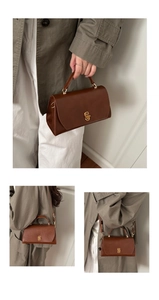 Detail of vintage brown leather square bag featuring a gold interlocking clasp and top handle