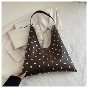 Detailed view of dark brown leather shoulder bag with golden metallic rivets decoration