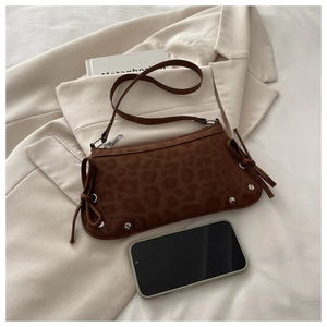 Detail of leopard print shoulder bag with silver studs, side bows, and compact size