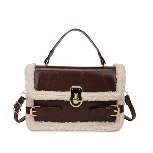 Brown leather crossbody bag with cream fleece trim and gold clasp on white background