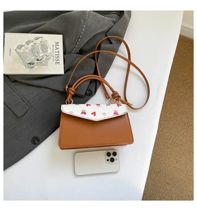 Detailed size comparison of the printed leather crossbody bag next to a smartphone