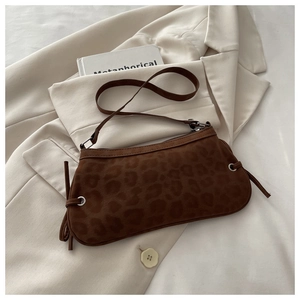 Detail of leopard print suede shoulder bag with silver eyelet accents on a beige blazer