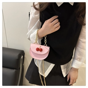 Detailed shot of pink mini crossbody bag with 3D cherry accents and gold chain strap