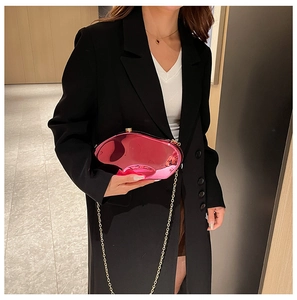Borsa da sera irregolare in acrilico fucsia con catena dorata su abito nero