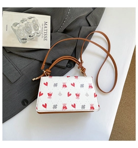 Detailed close-up of white crossbody bag with cute pink bear and red heart patterns