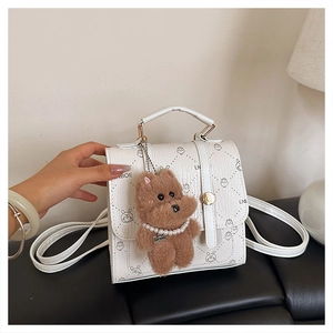 Detail of white textured PU bag with cartoon prints and a brown plush bear charm