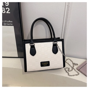 Detail of checkered tote bag with fashion label and silver chain strap on table