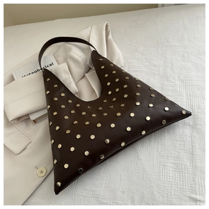 Detail of dark brown hobo bag featuring gold rivet accents on matte leather surface