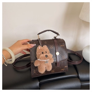 Detail of vintage brown textured leather backpack with gold hardware and plush charm