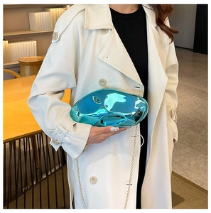 Dettaglio di una borsa da sera metallica blu fluida con una tracolla dorata