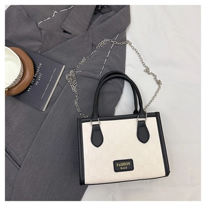 Detail of checkered tote bag with black leather trim next to a coffee cup and blazer