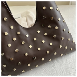 Macro shot of dark brown leather tote bag with dense golden round metal rivets details