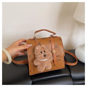 Detail of caramel faux leather bag with LNBOE prints and a cute plush bear charm