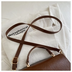 Detail of vintage brown textured leather handbag with gold metal hardware on fabric