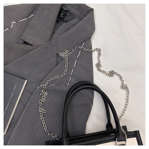 Detail of a chic monochrome tote bag with silver chain strap and grey blazer texture