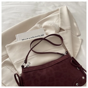 Close-up of burgundy leopard print shoulder bag with ribbon bow and silver rivets
