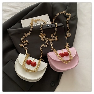 Detail of leather crossbody bags with cherry charms and gold chain handles