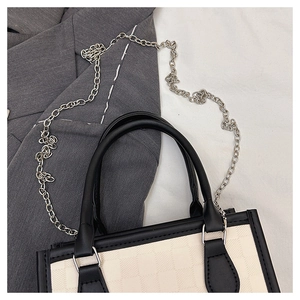 Close-up of checkered tote bag with black leather trim and silver chain strap details