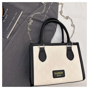 Detail view of checkerboard tote bag with black leather trim and metal chain strap