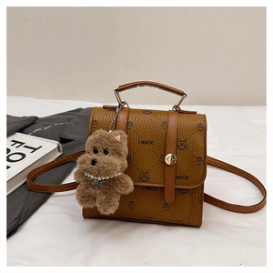 Close-up of brown pebbled leather backpack with cartoon prints and plush bear charm